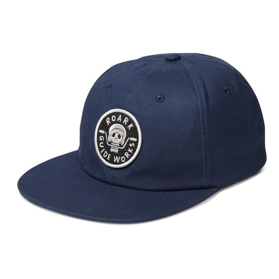 side videw of blue baseball hat with small circular logo on the center of the front two panels.
