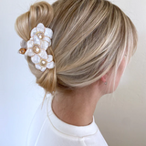 FLORAL CLAW CLIP HOLIDNG UP A PERSONS HAIR.