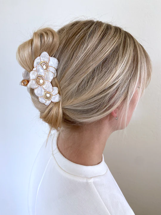FLORAL CLAW CLIP HOLIDNG UP A PERSONS HAIR.