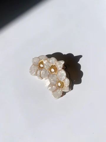 SET OF THREE WHITE NARCSSUS FLOWERS WITH GOLD LIKE TRIM MAKE A SOFT U-SHAPE. THE CLIP SITS AGAINST A PLAIN WHITE BACKGROUND.
