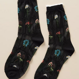 a pair of black sheer socks with 5 different types of flowers delicately embroidered in a grid-like pattern. 