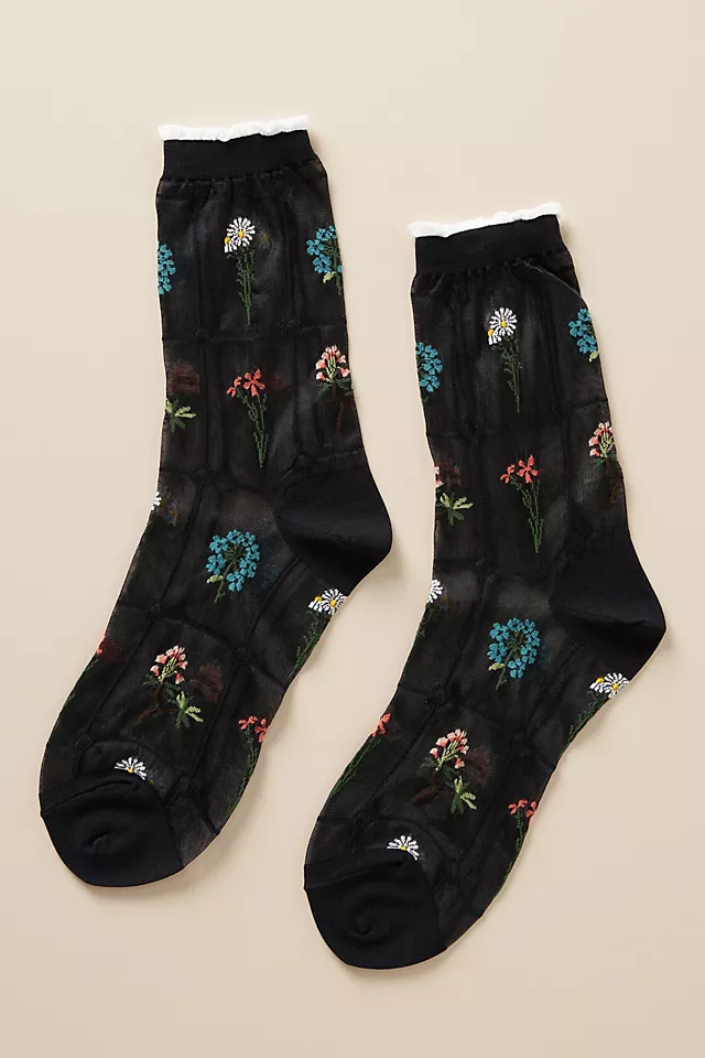 a pair of black sheer socks with 5 different types of flowers delicately embroidered in a grid-like pattern. 