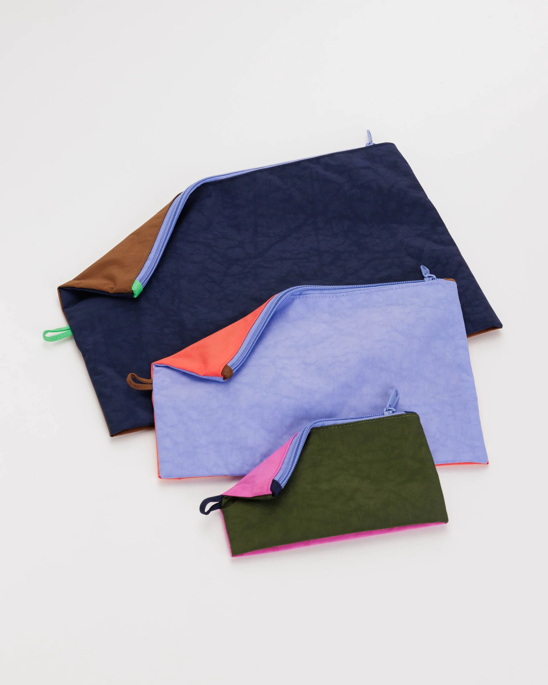 Set of 3 pouches in varying size and colors, laid flat to show size range. 