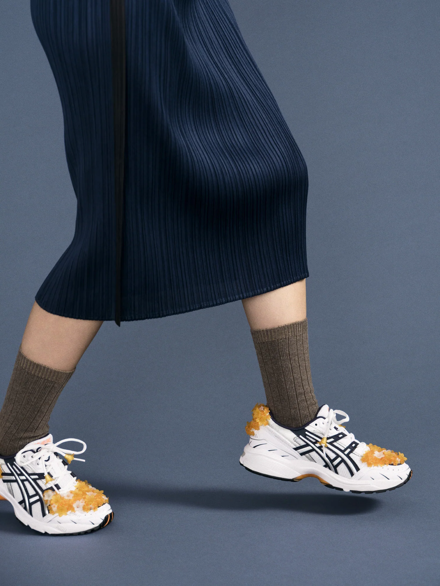brown cashmere socks are paired with a skirt and tennis shoes. 