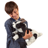 young child holds the goat hand puppet  in his arms while smiling.
