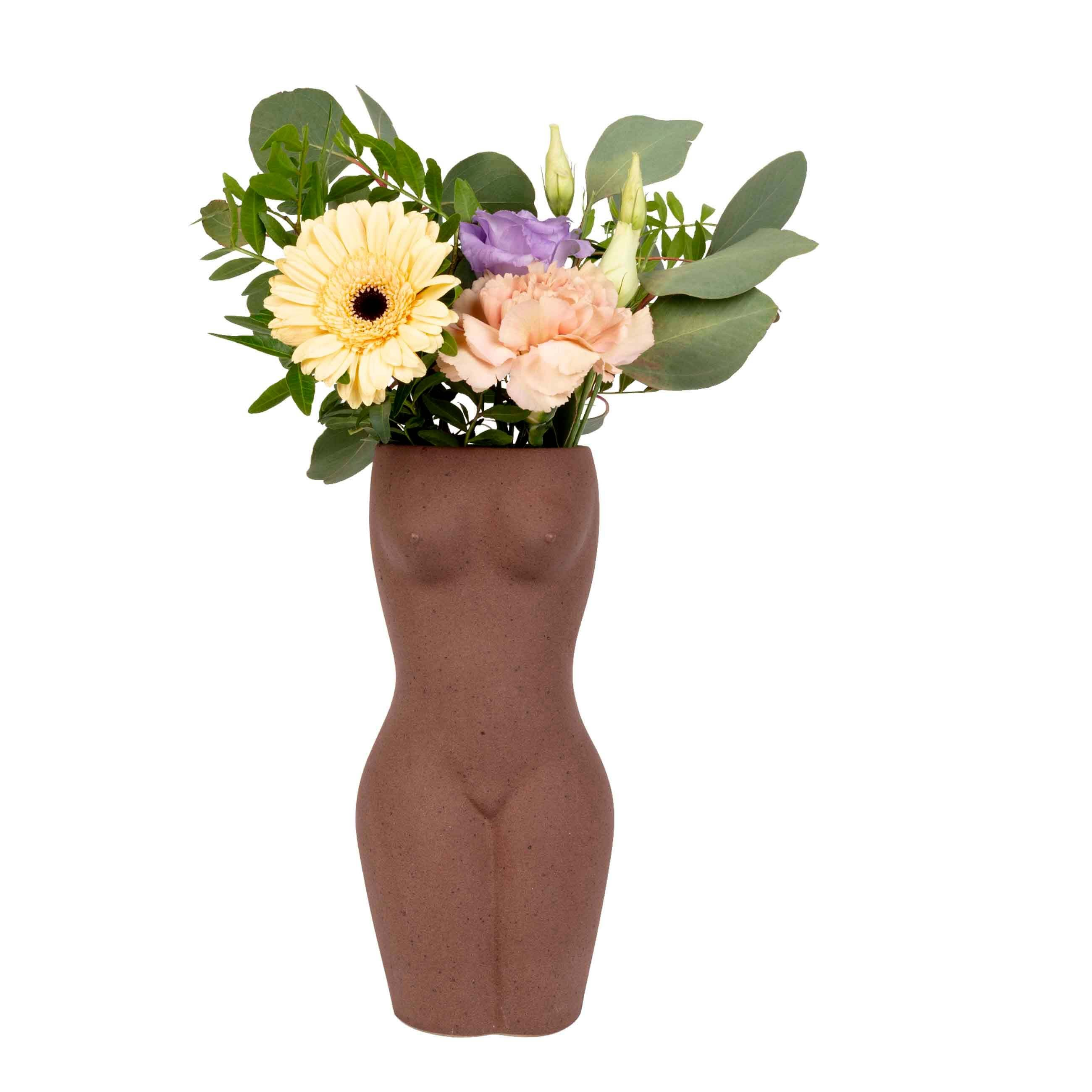 body vase in front of white background. Different types of flowers are being displayed inside the vase. 