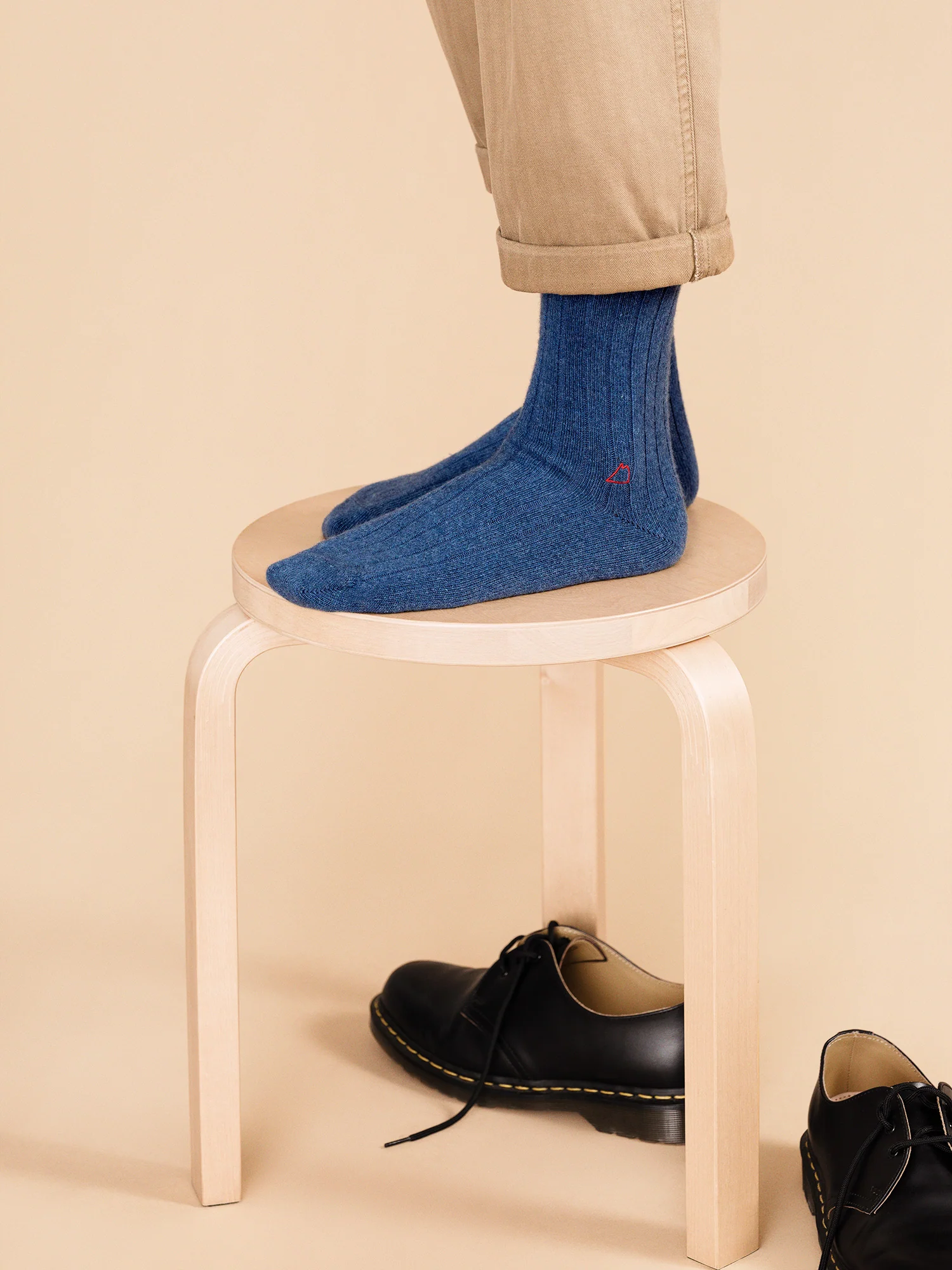 person wearing blue socks stands on a small stool. 