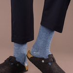 image shows a person from the knees down. the person is wearing dark blue plants and dark shoes with the blue socks providing a nice contrast between the other items.