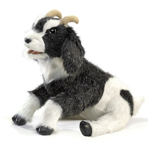 Small  hand puppet thats a peppered color goat. Sitting at a diagonal, mouth ajar, infront of a white background. 