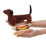 Dachshund puppet in one hand, hotdog bun and sauces in the other hand to show the bun is removable. 
