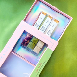 The Matcha Kit displayed with the insert pulled halfway out of the box. Iridescent colors shine off the inside of the box. The box is laid in top of a green background that varies in shades of green. 