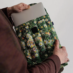 Person pulling laptop out of case that has grass and florals on the print. 