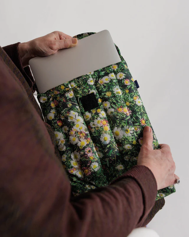 Person pulling laptop out of case that has grass and florals on the print. 