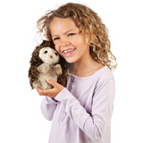 young child holding the hedgehog puppet lovingly. 
