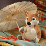 shiba inu puppy puppet relaxing on blankets  with an umbrella casting shade from the sun. 