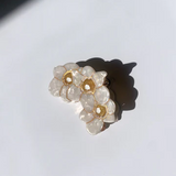 SET OF THREE WHITE NARCSSUS FLOWERS WITH GOLD LIKE TRIM MAKE A SOFT U-SHAPE. THE CLIP SITS AGAINST A PLAIN WHITE BACKGROUND.