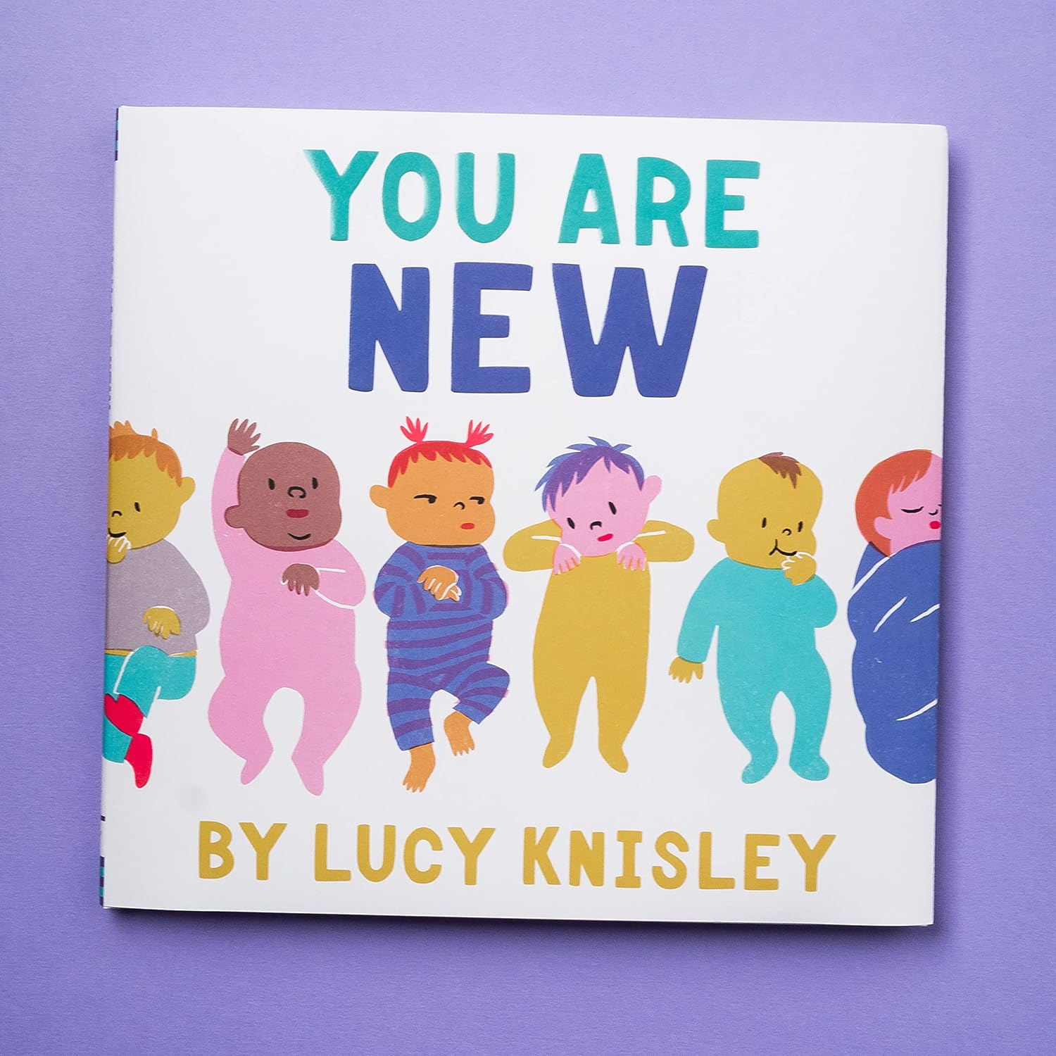 COVER ART OF BOOK SHOWING SIX BABIES WEARING DIFFERENT OUTFITS ALL L AYING DOWN IN DIFFERENT POSITIONS.