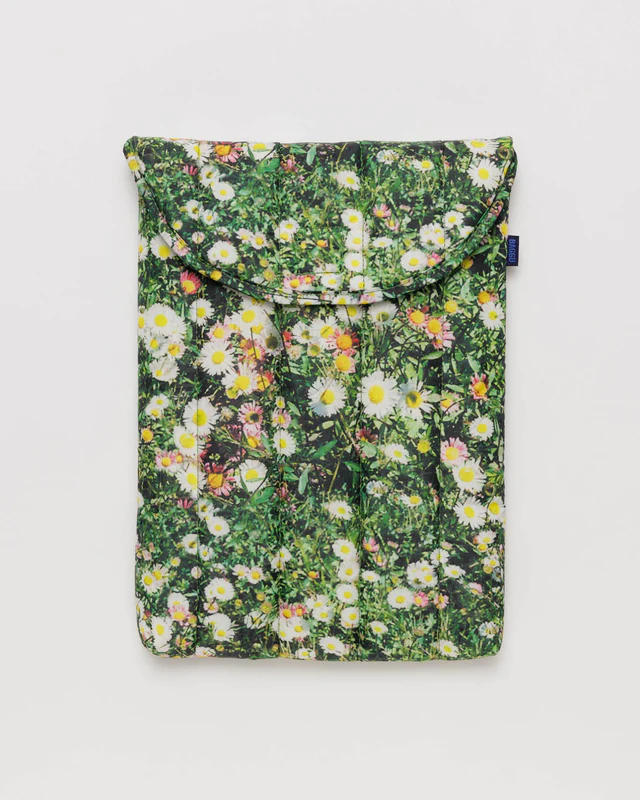 laptop case with flower and grass print in front of white background. 