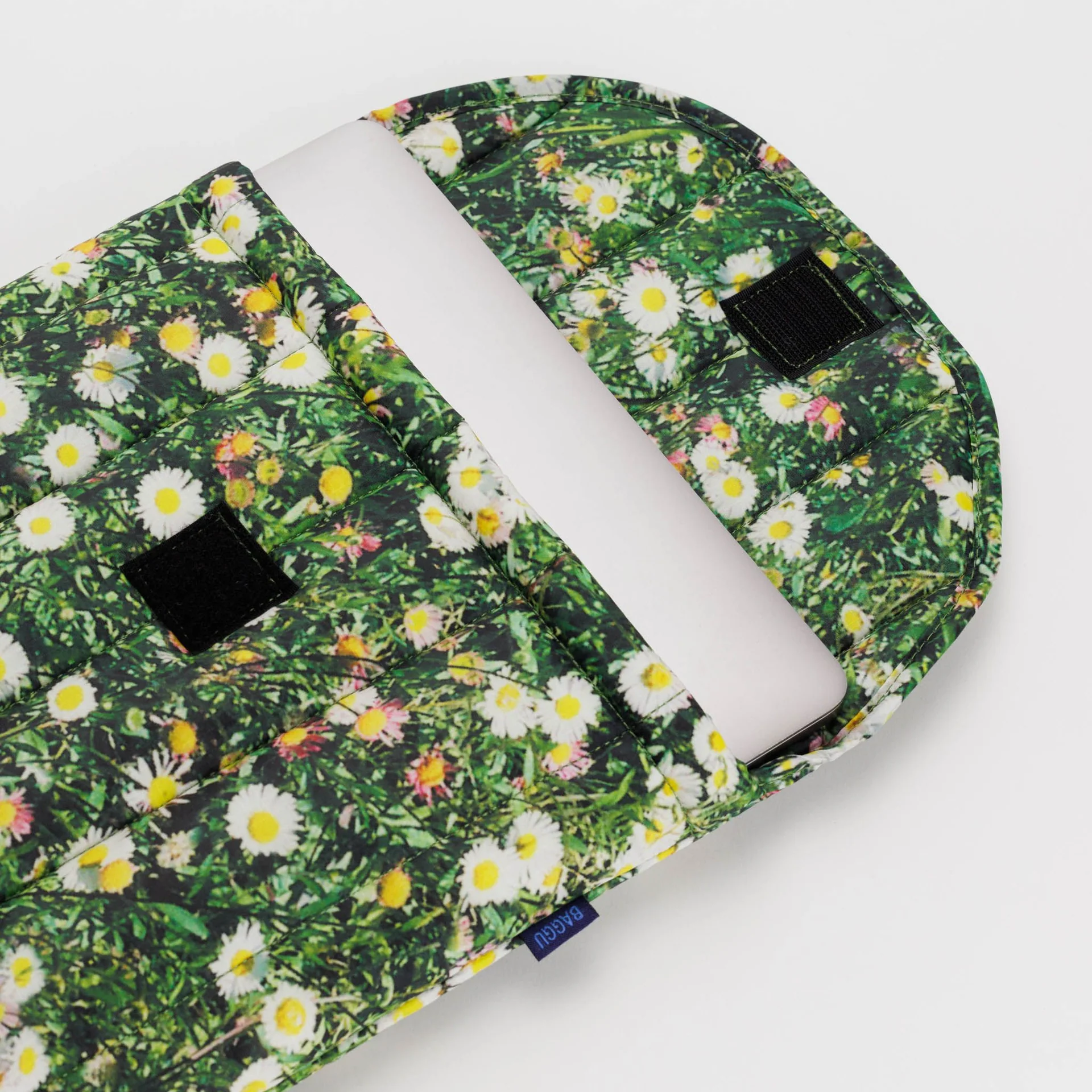 Laptop peeking out of lapto case. Floral/ grass details pop against white background. 