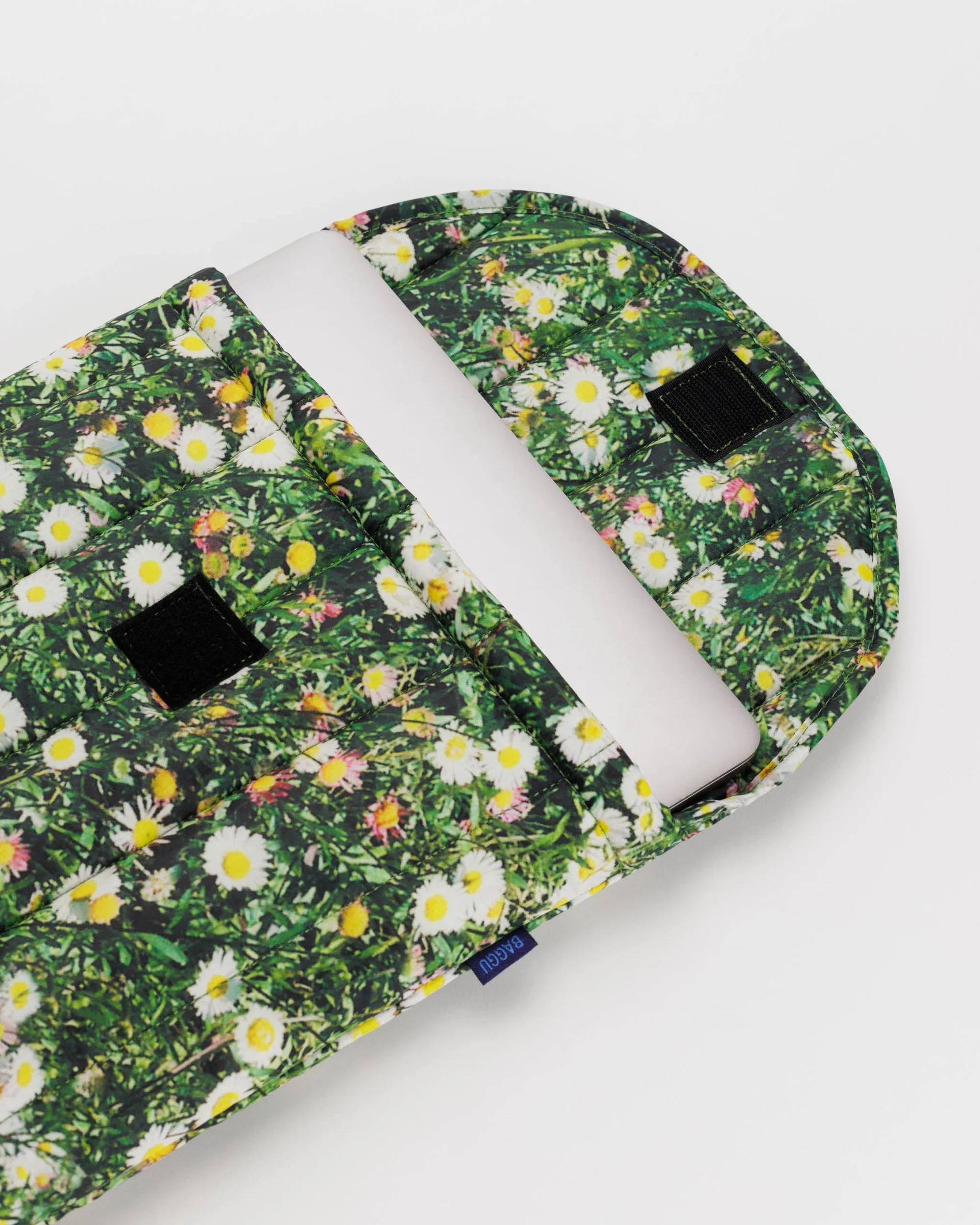 Laptop peeking out of lapto case. Floral/ grass details pop against white background. 